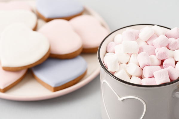Mug of Marshmallows Stands Next to Plate of Heart-Shaped Gingerbread